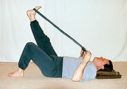 Student stretching his leg with a strap, one leg in the air