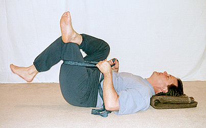 Student stretching his leg with a strap around one thigh